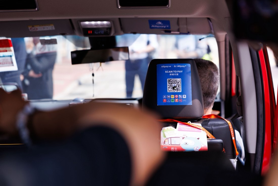 Taxi headrest screen showing the Alipay SCAN TO PAY QR code — the everyday scene a bound card unlocks