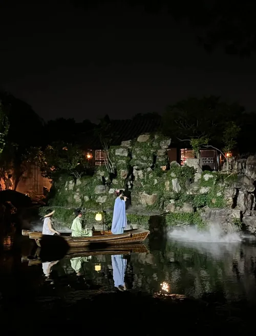 Master of the Nets Garden night show: performers in costume on a misty pond, lantern-lit